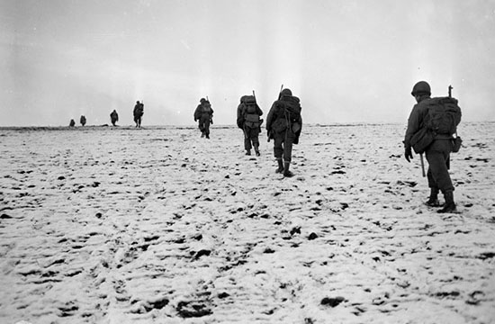Troops from the 137th Infantry Regiment, 35th Division, moving accross snow covered field near Luxemberg-Belgium border. Photo courtesy kansasmemory.org.